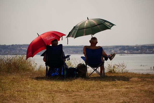 People sheltering under umbrellas from the sun in St Michael’s Bay in Cornwall