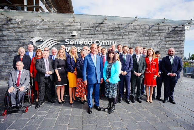 Reform UK leader Nigel Farage posing for a photo with Helen Jenner and colleagues in Cardiff