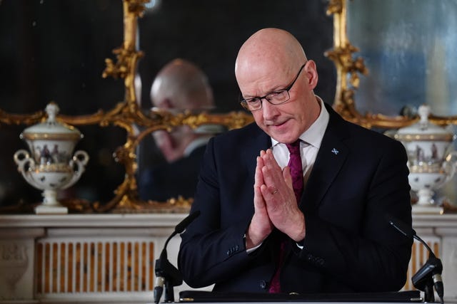 John Swinney with hands clasped together as he speaks at a lectern in Bute House