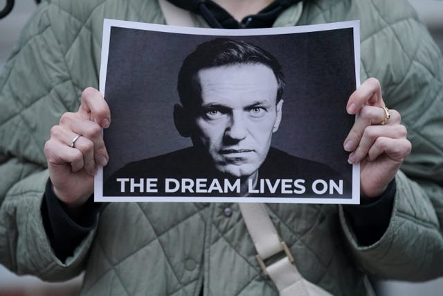 A protester holds a picture of Alexei Navalny at a protest opposite the Russian Embassy in London. The words "The dream lives on" are printed below Navalny's face.