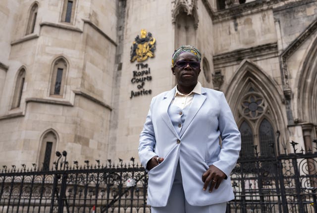 Rosamund Adoo-Kissi-Debrah in pale blue trouser suit next to black railings outside the Royal Courts of Justice