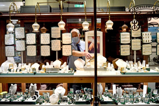 A jeweller removes jewellery from his window