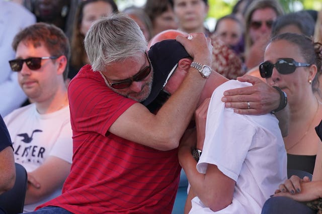 The family of Barnaby Webber, father David (left) and brother Charlie, embrace during the vigil. 