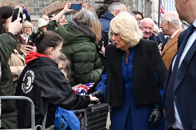 Camilla shaking hands with a young girl among well-wishers