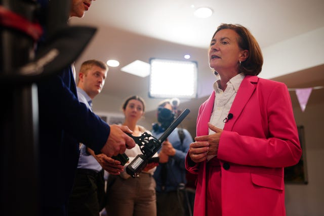 Eluned Morgan in pink suit speaking into a microphone at the Caer Heritage Centre