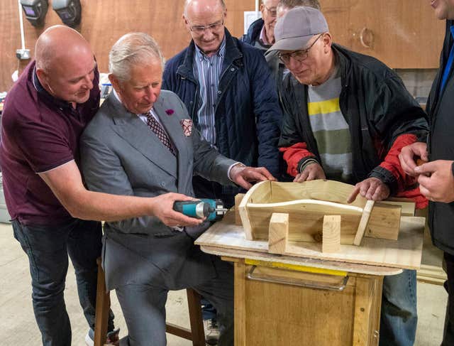 The Prince of Wales used a power driver to put screws into an ornamental wheelbarrow during a visit to the Owenkillew Community Centre in Gortin (Steve Parsons/PA)