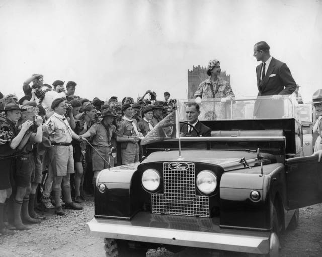 The Queen and the Duke of Edinburgh drive in an open Land Rover