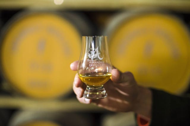 A hand holding an Annandale Distillery glass containing whisky