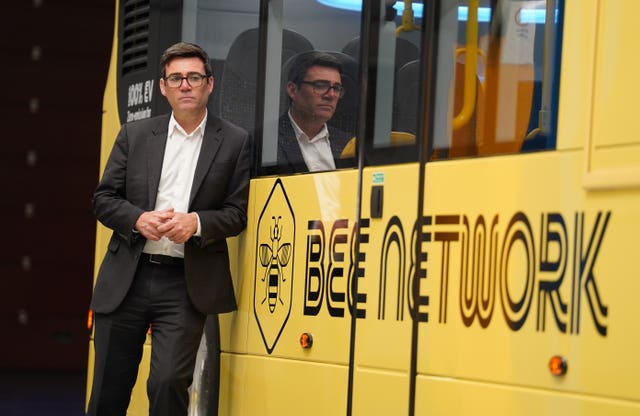 Andy Burnham standing next to a yellow Bee Network bus