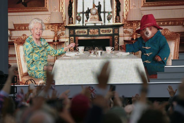 Crowds watch a film of Queen Elizabeth II having tea with Paddington Bear on a big screen during the Platinum Party at the Palace