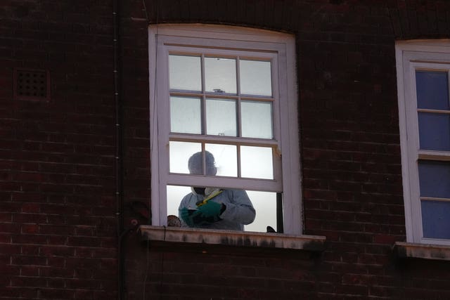 A forensic investigator at the window of a property 