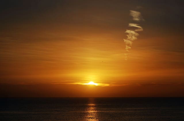 A plane contrail is seen as the sunrises over Whitley Bay on the north east coast.