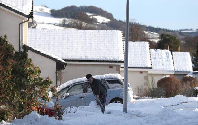 A man clears his driveway in Darnick, with delays likely for travelling motorists (Andrew Milligan/PA)