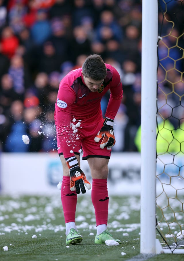 Livingston goalkeeper Max Stryjek is hit by a snowball thrown from the stand