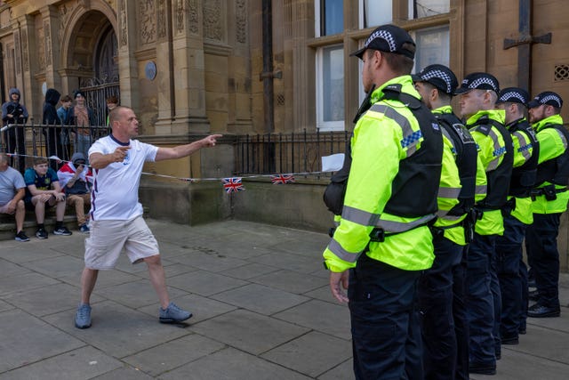 A man stands in front of a line of police