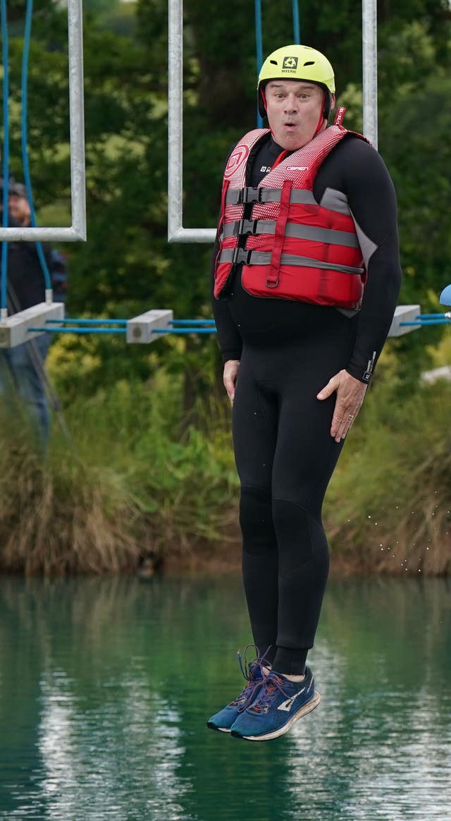 Sir Ed Davey, wearing a wetsuit and life jacket, jumps into open water