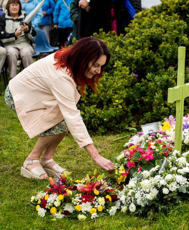 Mary Hornsey lays a yellow rose at the memorial cross 