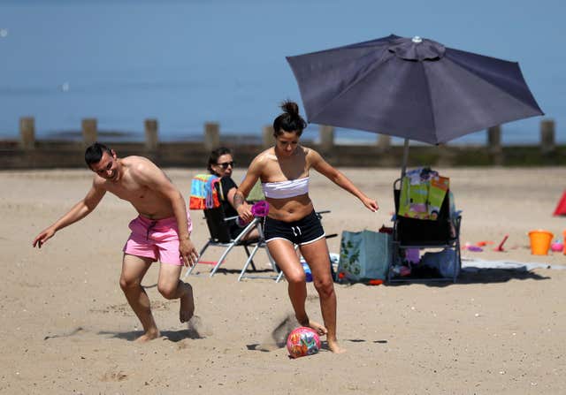 A couple play football on Portobello beach as they enjoy the hot weather (Andrew Milligan/PA)