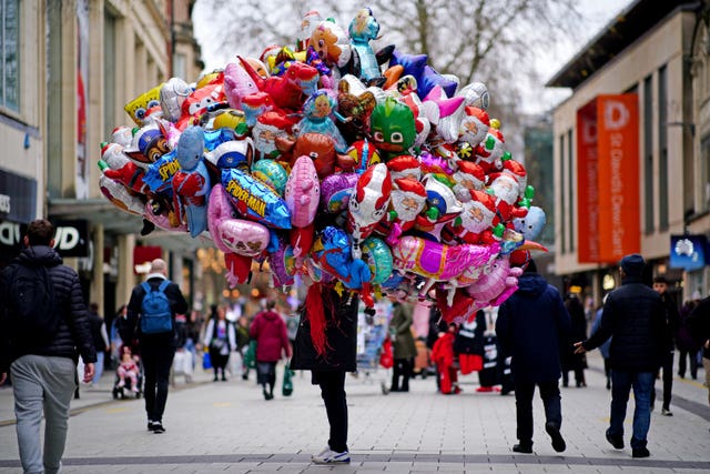A balloon vendor is passed by Christmas shoppers in the centre of Cardiff in December