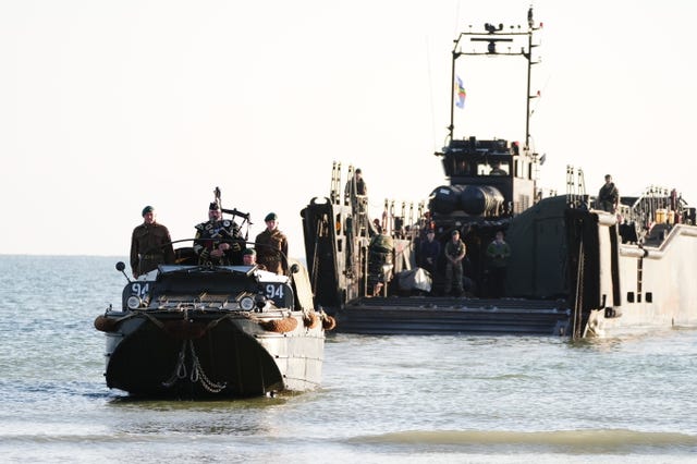 Military piper Major Trevor Macey-Lillie comes onto shore on a DUKW amphibious vehicle ahead of playing a dawn lament on Gold Beach in Arromanches in Normandy, France