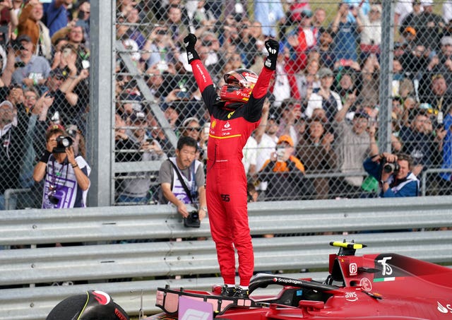 Carlos Sainz stands on top of his car in celebration