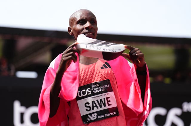 Sabastian Sawe displays his running shoe marked with '1:59.30 WR sub 2' after winning the London Marathon