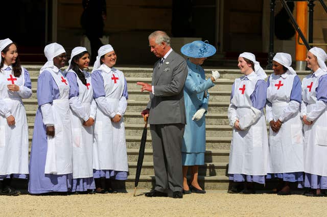 The Prince of Wales and Princess Alexandra pose with nurses dressed in First World War uniforms during a Buckingham Palace garden party