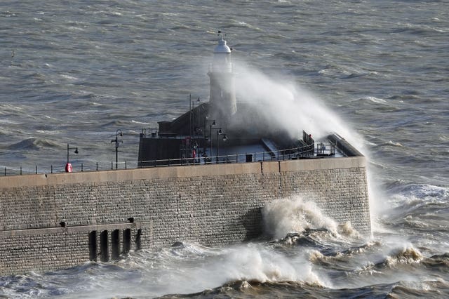 Waves crash over the harbour wall