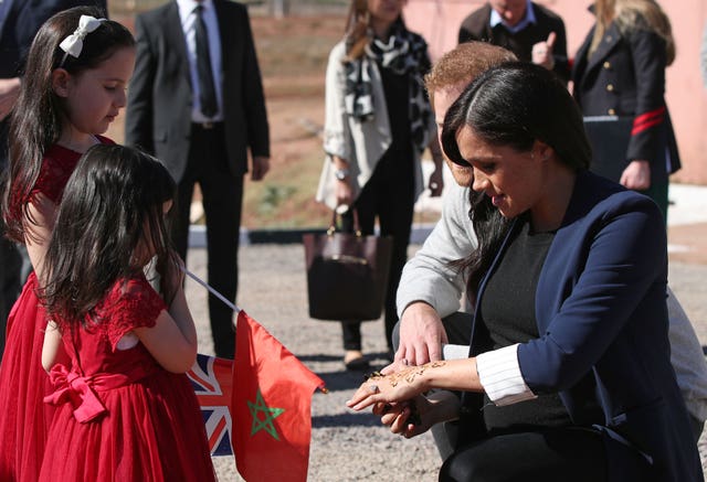 The Duchess of Sussex shows two girls her henna design