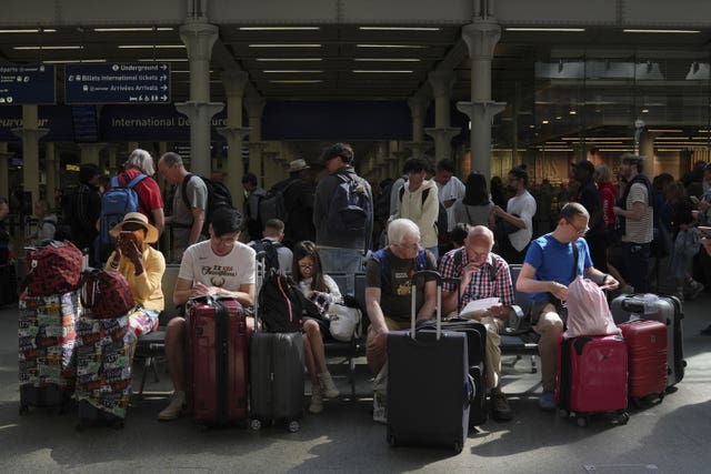 Passengers sit with suitcases