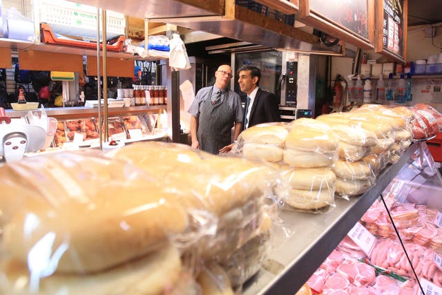 Rishi Sunak (right) speaks to a butcher during a visit to Bury market