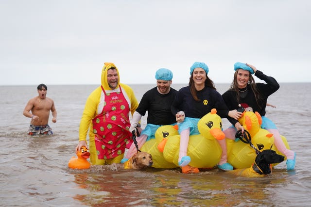 Swimmers in the sea dressed in shower caps and riding inflatable ducks