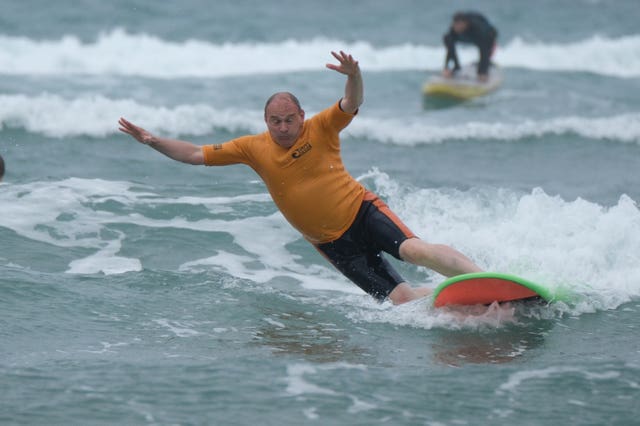 Sir Ed Davey falls from a surfboar