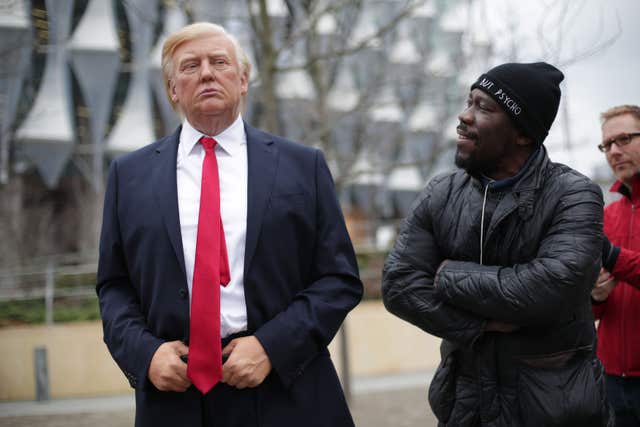 A man stands next to the Madame Tussauds wax figure of US President Donald Trump outside the new US Embassy in Nine Elms, London (Yui Mok/PA)