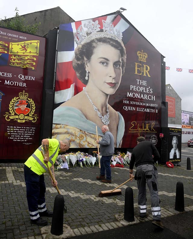 Council workers and local community representatives clean up an area on Crimea Street off the Shankill Road in Belfast for people to lay flowers 