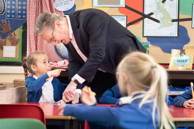 Sir Keir Starmer squeezes toothpaste onto a piece of paper while a young girl holding a toothbrush points at him during a General Election campaign event