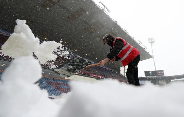 Snow is cleared from the pitch at Turf Moor before Burnley's match against Tottenham was postponed