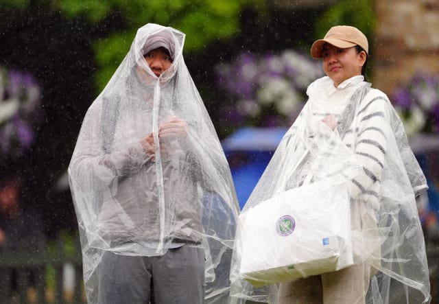 Spectators shelter from the rain on the hill at Wimbledon