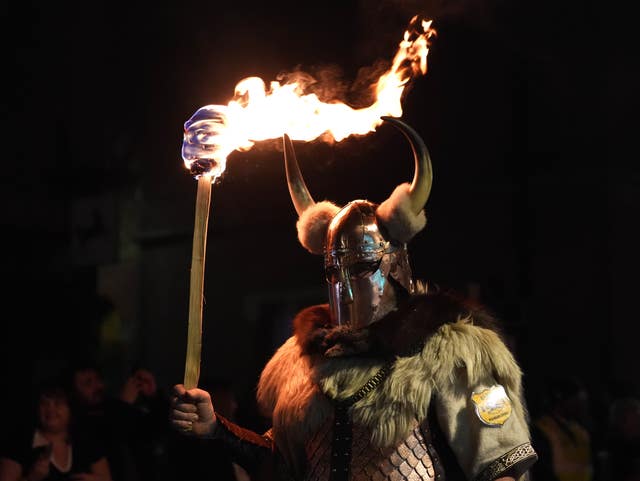 A man in a horned helmet holding a flaming torch