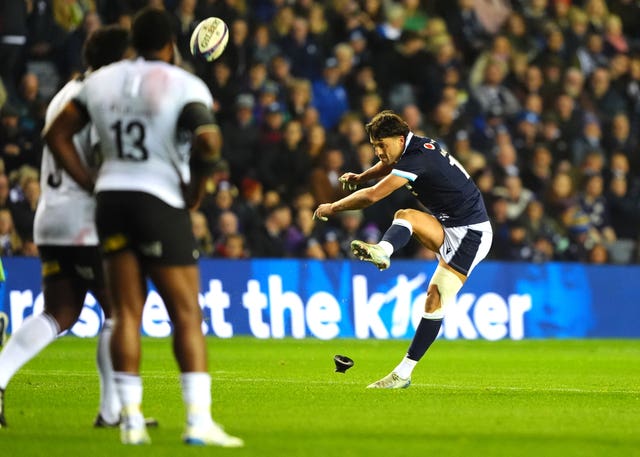 Adam Hastings kicks a penalty as a Fiji player looks on