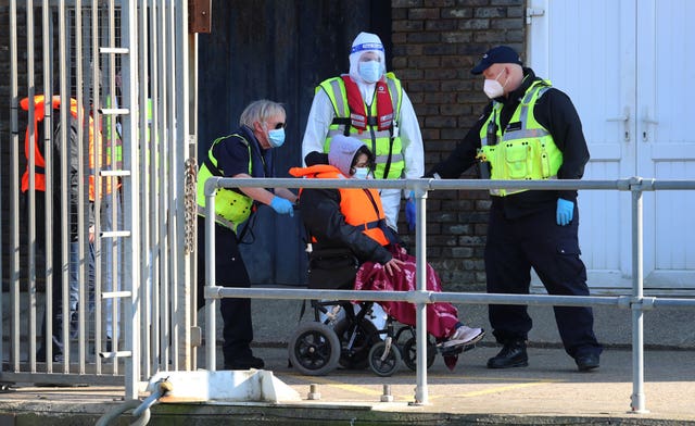 Border Force officers wearing PPE escort a group of people thought to be migrants as they are brought in to Dover, Kent