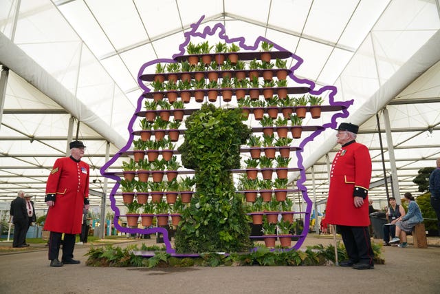 Chelsea Pensioners Ted Fell, left, and George Reid pose beside florist Simon Lycett’s The Queen’s Platinum Jubilee, a purple metal display shaped like the profile of Queen Elizabeth II containing 70 hand-thrown terracotta pots, one for each year of the Queen’s reign, and each planted with a Lily of the Valley, during the RHS Chelsea Flower Show press day at the Royal Hospital Chelsea, London