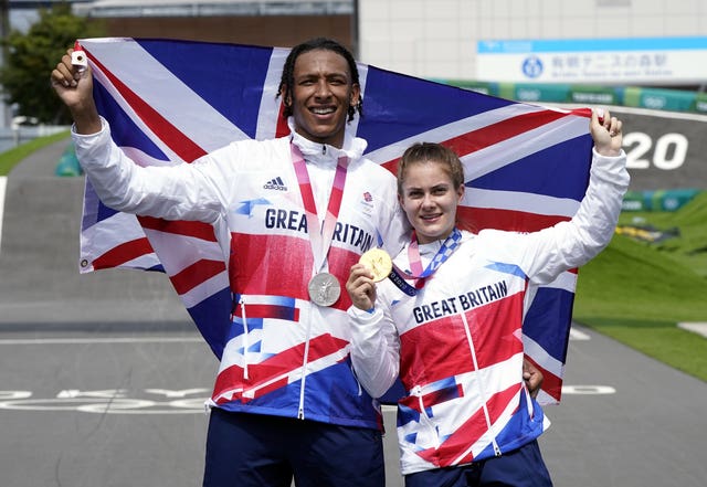 Kye Whyte and Beth Shriever, with a Union Jack flag wrapped around them, pose for pictures with their medals in Tokyo
