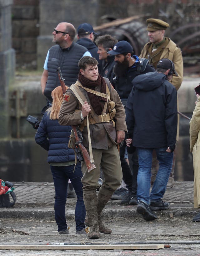 An actor slings a rifle over his shoulder between takes