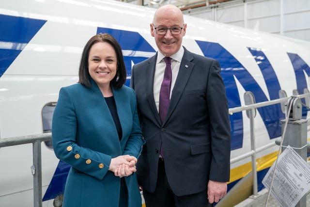 John Swinney and Kate Forbes smiling, while standing in front of a Ryanair plane