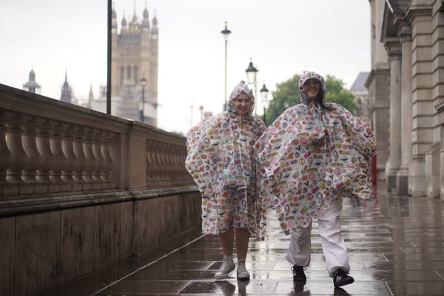 Tourists wear rain ponchoes to protect against the wet weather as they walk along Whitehall in Westminster, central London