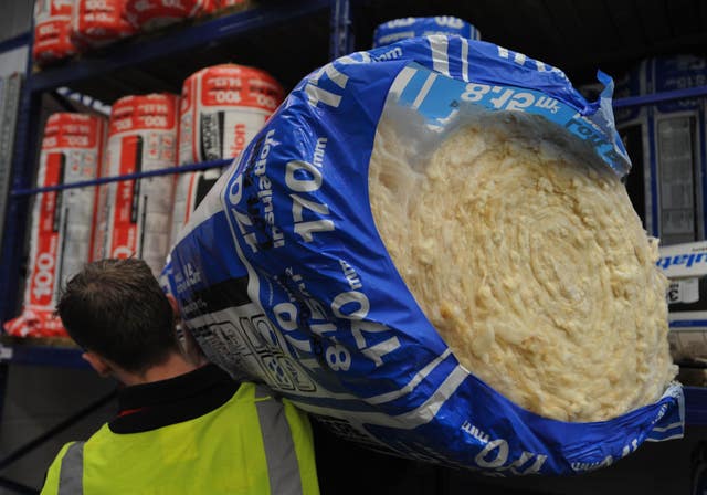 A man carries a roll of loft insulation