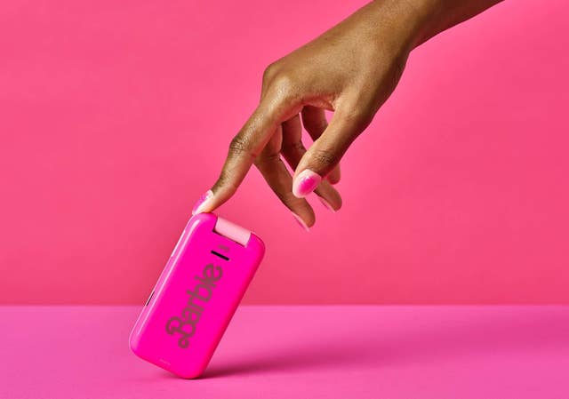 A hand holding up the closed Barbie flip phone