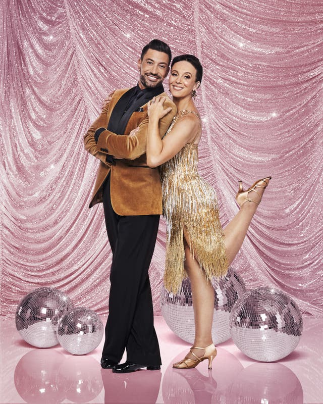 Giovanni Pernice and Amanda Abbington pose against a pink backdrop as they smile to the camera