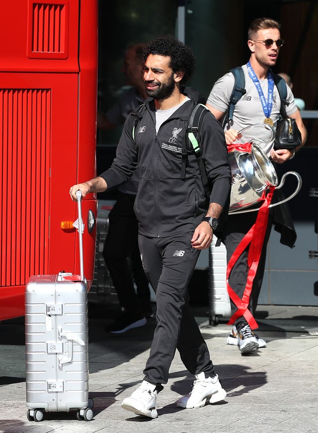 Mohamed Salah, left, leaves Liverpool's hotel as Jordan Henderson follows with the Champions League trophy